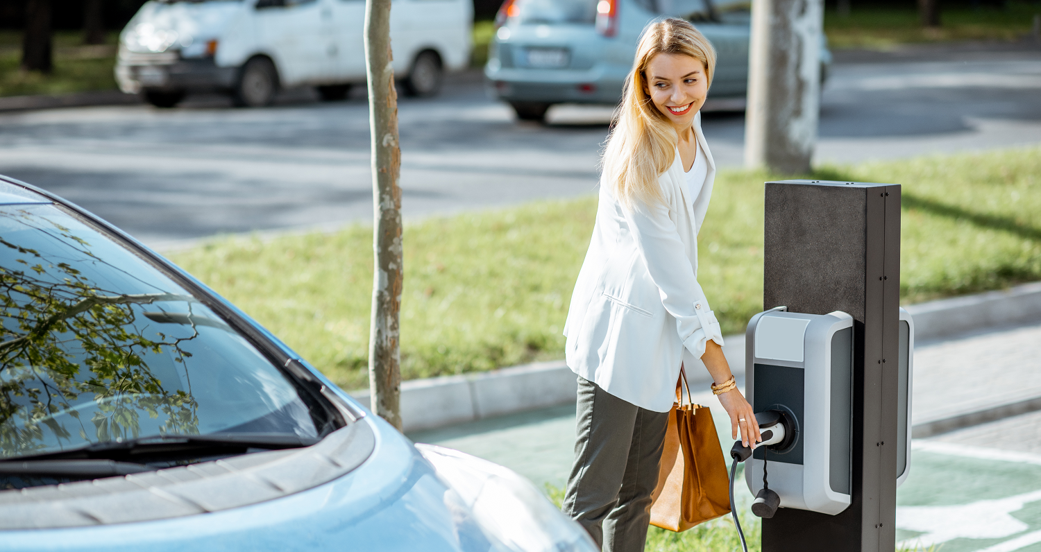 Frau lädt ein Elektroauto an einer Ladestation